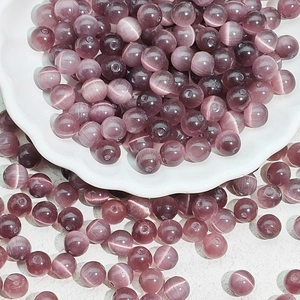 Macro shot of round purple cat's eye glass beads with fiber optic effect in a ceramic dish