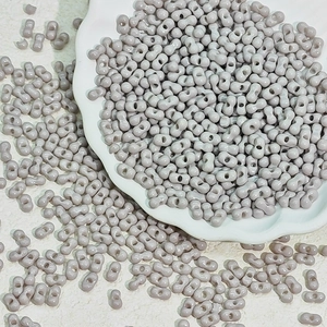 Detailed view of 3x6mm twin-hole lavender glass beads in a white ceramic dish