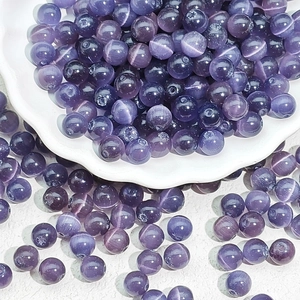 Macro view of purple cat eye glass beads for DIY jewelry making in a white ceramic bowl
