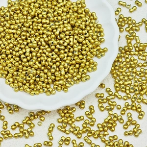 Macro detail of gold-plated dumbbell-shaped dual-hole seed beads for DIY jewelry making