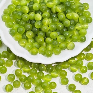 Close-up of green cat-eye glass beads with optical effect for DIY jewelry making