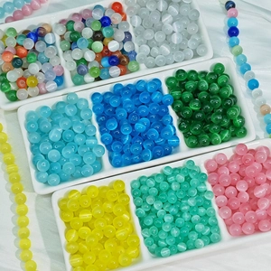Macro view of colorful cat eye glass beads for DIY jewelry making on white silk