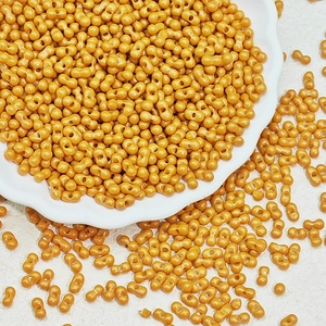 Macro shot of mustard yellow dumbbell-shaped double-hole beads on a white decorative tray