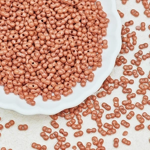 Macro shot of 3x6mm matte cinnamon peanut beads with double holes in a white ceramic dish