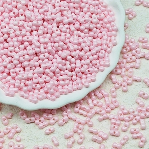Macro shot of 3x6mm pink dual-hole glass beads for DIY jewelry making in a decorative dish