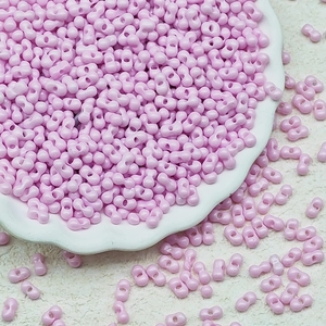 Macro shot of 3x6mm pink dual-hole peanut glass beads in a decorative white dish