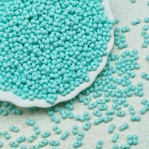 Macro shot of turquoise twin seed beads in a white ceramic tray for DIY jewelry making