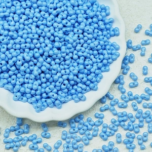 Close-up of sky blue peanut glass beads in a white floral dish for DIY jewelry making