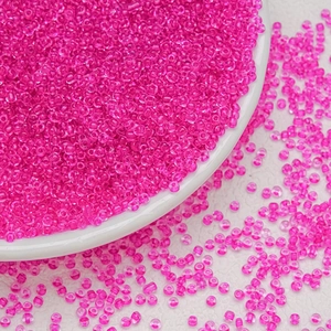 Macro shot of 3mm rose pink glass seed beads for DIY jewelry making in a white bowl