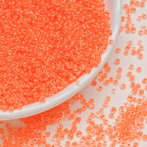 Macro shot of 3mm translucent orange glass seed beads for handmade jewelry DIY projects