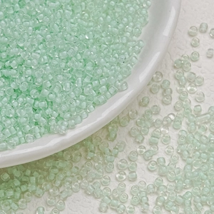 Macro view of 3mm light green translucent glass seed beads for DIY jewelry making