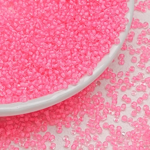 Macro shot of 3mm neon pink glass seed beads for DIY jewelry and earring making