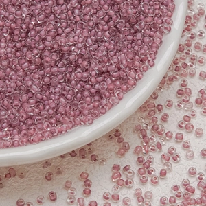Macro view of translucent 3mm pink-purple glass seed beads for DIY jewelry craft