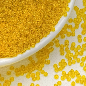Macro detail of 3mm bright yellow transparent glass seed beads for DIY jewelry making