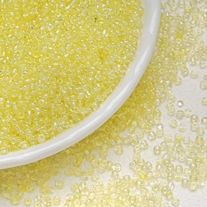 Macro shot of 3mm light yellow transparent glass seed beads with AB iridescent coating in a bowl