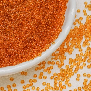 Macro shot of transparent orange 3mm glass seed beads for DIY jewelry making and crafts