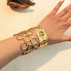 Brazalete abierto hueco bañado en oro de 18K con textura martillada en la muñeca de modelo
