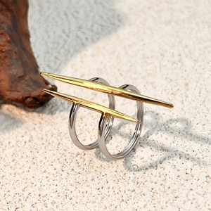 Anillo geométrico bicolor de acero inoxidable con detalle dorado sobre arena blanca