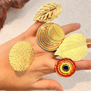 Bohemian gold plated leaf rings and colorful enamel band set on textured fabric