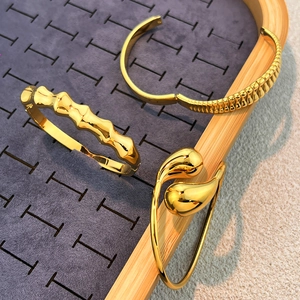 Drei goldene Edelstahl-Armreifen mit Webstruktur und Wassertropfen-Design im Set