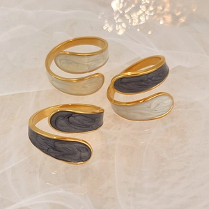 Goldene Spiralringe mit Marmor-Emaille auf einem weichen weißen Organza-Hintergrund