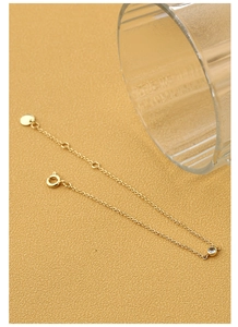 Detail eines dünnen Gold-Zirkon-Armbands mit verstellbarer Kette auf gelbem Grund