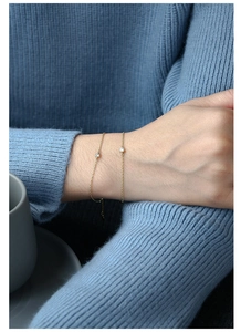 Detail eines minimalistischen Goldkettenarmbands mit rundem Zirkonia-Stein in Fassung
