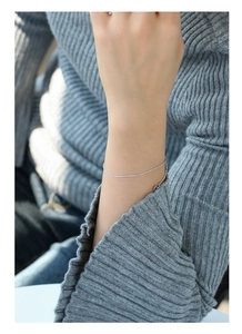 Bracciale a catena d'argento minimalista con barra lucida su modella in maglione grigio