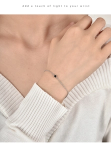 Nahaufnahme eines minimalistischen Silberarmbands mit schwarzer Perle am Handgelenk