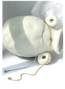 Dettaglio di bracciali minimalisti oro e argento su un vaso con sottili tubi metallici