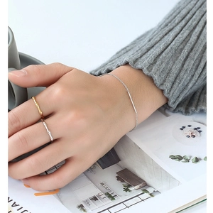 Set minimalista bracciale placcato oro e anelli stile bambù indossati su maglia elegante