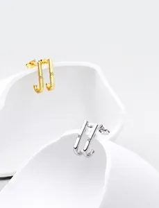 Macro shot of minimalist J-shaped curved stud earrings with inlaid diamond detailing
