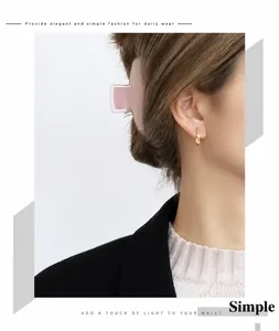 Detail of minimalist gold bar earrings with zircon stones worn by a model
