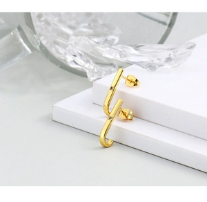 Close-up of gold J-shaped curved earrings featuring central micro-inlaid round zircon stones