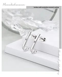 Detail of silver J-shaped stud earrings featuring micro-set zircon and thick K-gold plating