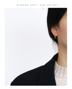 Minimalist gold J-hook earring with a small inset zircon shown on a model side view