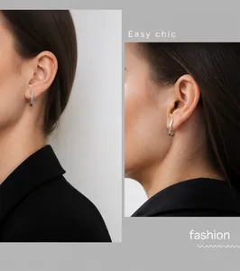 Close-up of minimalist silver J-hook earrings with polished metal finish on ear