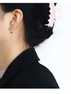 Macro shot of silver J-shaped earrings with sparkling diamond stud on model