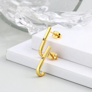 Minimalist gold J-hook stud earrings with diamond accents on a white display stand