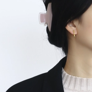 Minimalist long gold bar earrings with tiny diamond accent on a model's ear