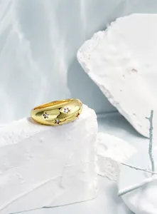 Detalle macro de anillo de estrella dorado con circonitas sobre mármol blanco