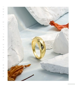 Detalle de un anillo ancho de oro con grabados de estrellas y circonitas sobre piedra