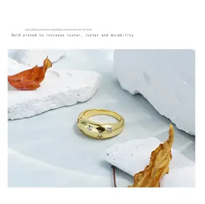 Detalle de anillo grueso bañado en oro con estrellas y circones sobre piedra
