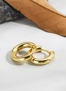 Close-up of polished 18K gold plated thick hoop earrings on a minimalist stone background