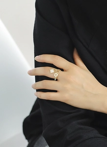 Dettaglio anello regolabile in oro 18K con catena cubana e ciondoli a forma di lucchetto