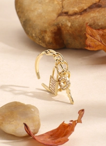 Dettaglio anello a catena in oro 18K con ciondoli a lucchetto e chiave in zirconi