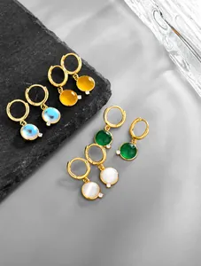 Macro view of four colorful geometric gemstone drop earrings on dark stone background