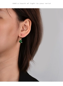 Detailed view of women's gold hoop earrings featuring round green natural stone and zircon
