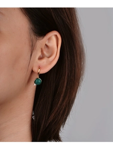 Detail of gold hoop earring with a round green malachite pendant and small zircon