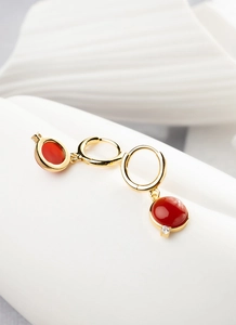 Detailed view of gold plated hoop earrings featuring round red stones and tiny zircon accent